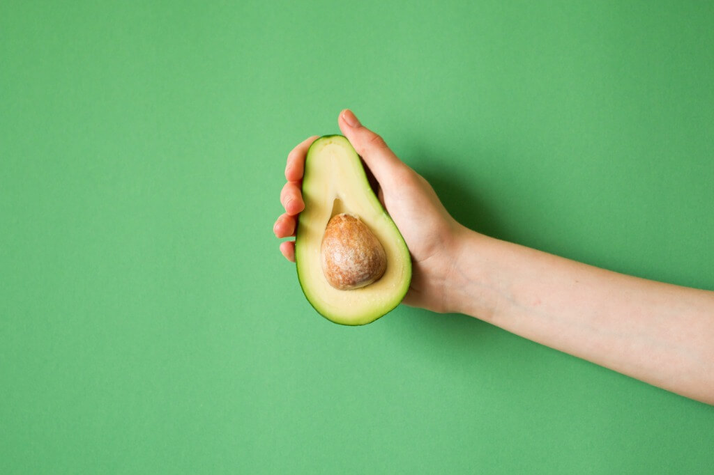 avocado-in-a-hand-of-woman-colored-background-healthy-food-concept-picture-id854288502